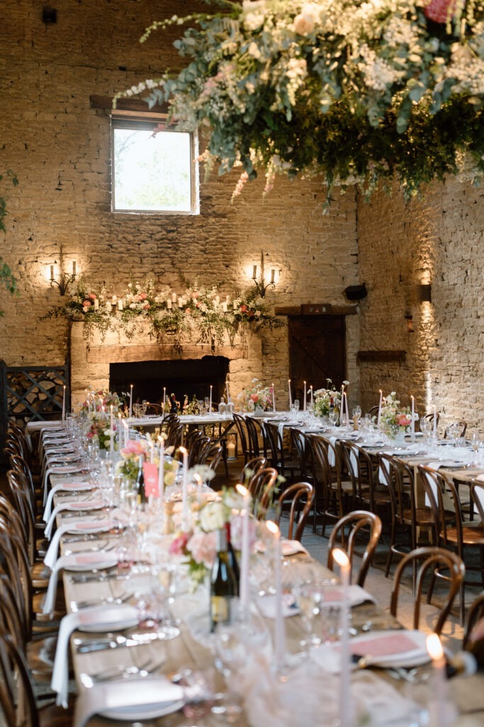 Cripps Barn’s ceremony space transformed for the wedding breakfast, with long tables and vibrant florals