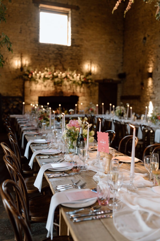 Cripps Barn’s ceremony space transformed for the wedding breakfast, with long tables and vibrant florals