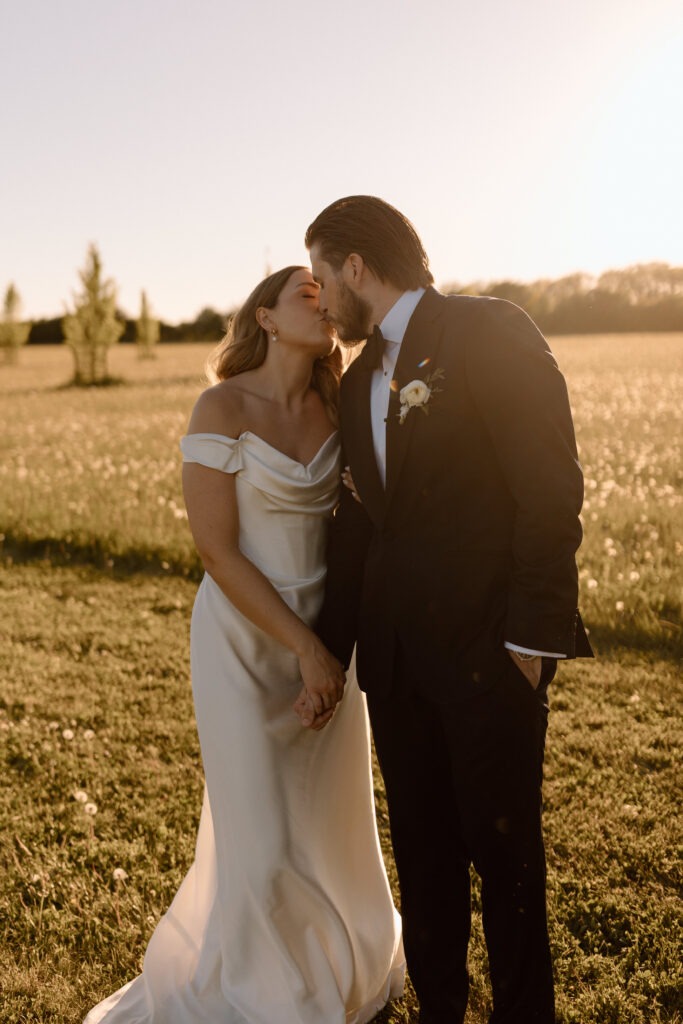 Katie and Jackson walking through wildflower-filled Cotswold fields near Cripps Barn at golden hour.