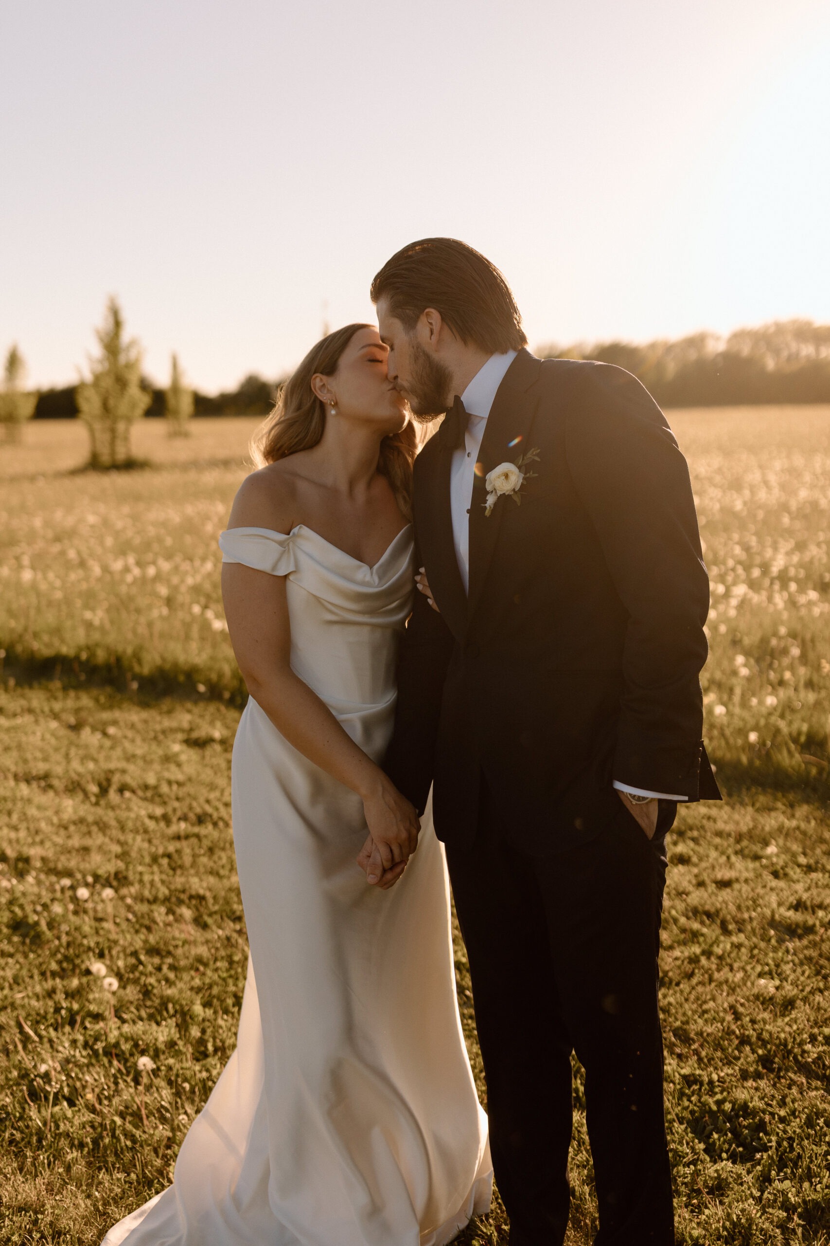 Katie and Jackson walking through wildflower-filled Cotswold fields near Cripps Barn at golden hour.