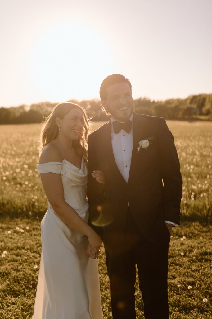 Katie and Jackson walking through wildflower-filled Cotswold fields near Cripps Barn at golden hour.