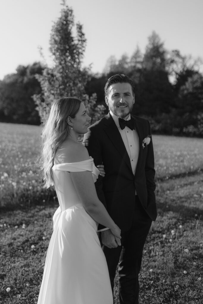 Katie and Jackson walking through wildflower-filled Cotswold fields near Cripps Barn at golden hour.