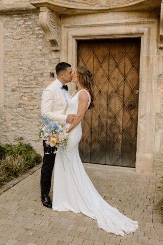 Couple posing for photographs with flowers in front of Kin House