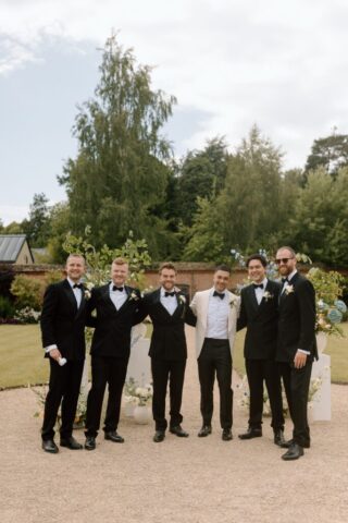 Groomsman assembling in front of florals ahead of wedding ceremony